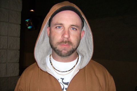 1981 Toyota Hilux - Man in a brown hooded sweatshirt with necklaces visible.