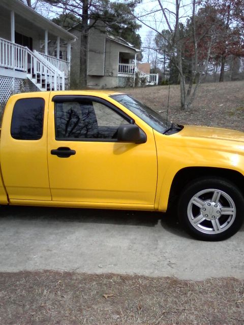 1981 Toyota Hilux - A yellow pickup truck is parked on a concrete driveway in front of a house.