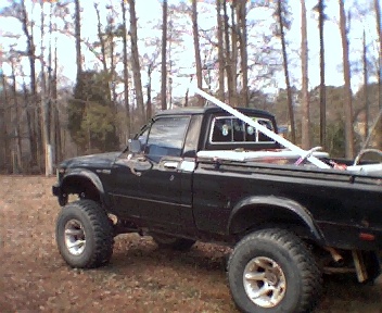 1981 Toyota Hilux - Black 1981 Toyota Hilux pickup truck with lifted suspension parked outdoors.