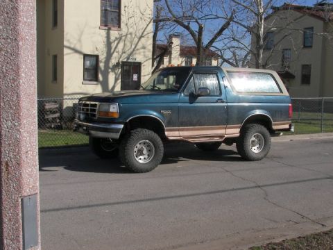 1995 Ford Bronco - This 1995 Ford Bronco features a teal body with tan trim and appears to be lifted with off-road tires.