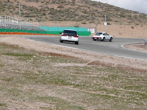 1992 Ford Taurus - Two cars are seen on a paved racetrack with bleachers and arid hills in the background.