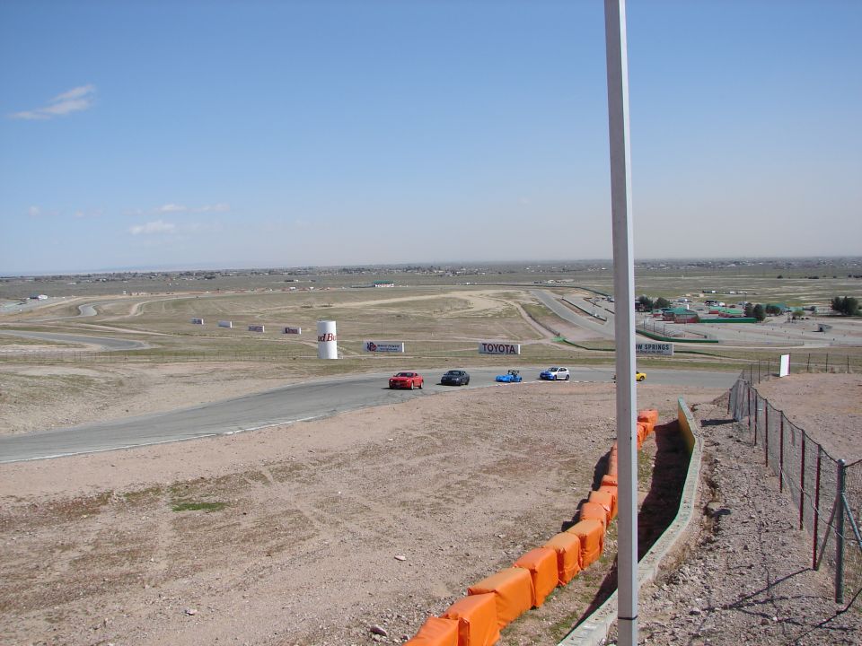 Race track with a red car, black car, blue car, and white car on the asphalt