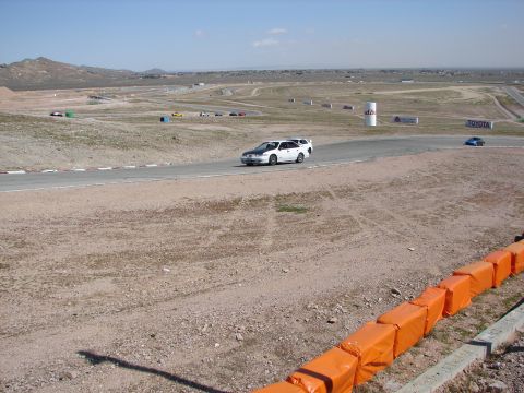 1992 Ford Taurus - A white station wagon drives on a race track with a blue car visible further down the course.