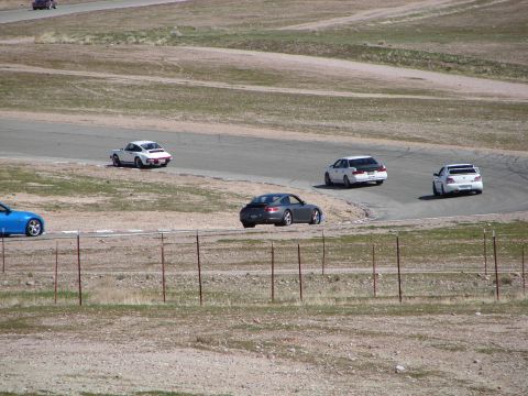 1992 Ford Taurus - Multiple vehicles are captured on a race track during a sunny day.