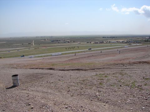 1992 Ford Taurus - A wide shot of a race track under a hazy sky, with several vehicles visible on the track and in the distance.