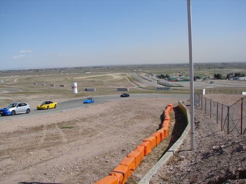1992 Ford Taurus - Multiple cars race on a track under a clear blue sky.