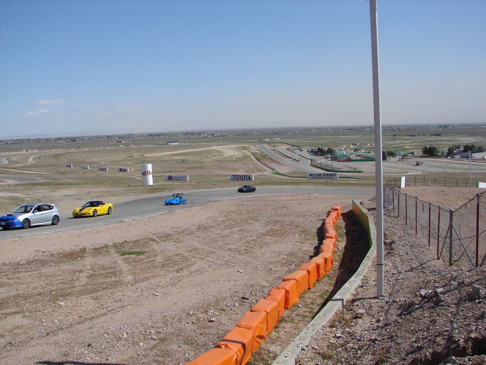 Race track with a blue Subaru WRX, yellow Chevrolet Corvette, blue open-wheel car, and black sedan
