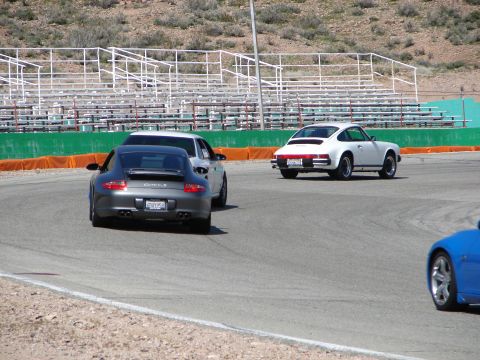 1992 Ford Taurus - Multiple Porsche 911s are seen on a race track with grandstands in the background.