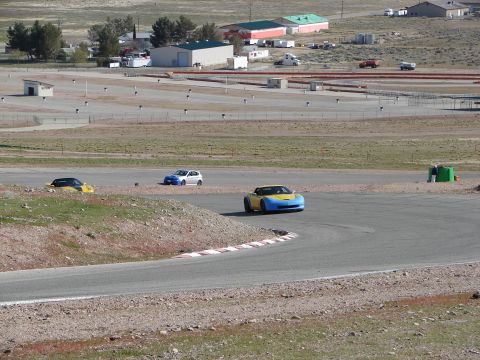 1992 Ford Taurus - A yellow and blue sports car navigates a turn on a race track, with other vehicles visible in the background.