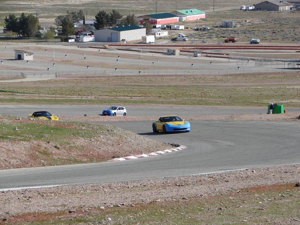 Yellow and blue sports car on a race track, viewed from the front-right