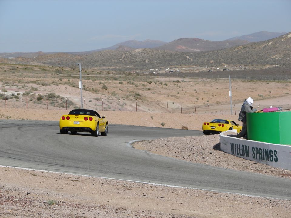 Yellow Chevrolet Corvette on race track, rear view. 2005 model