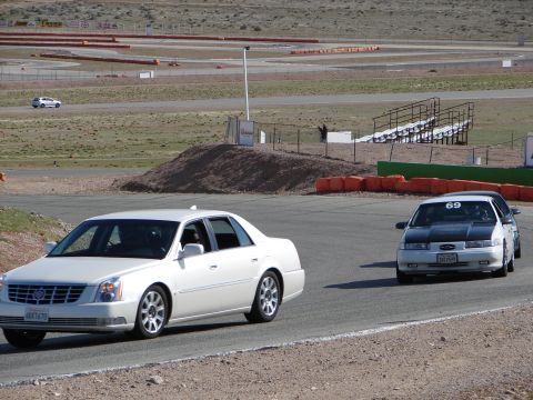 1992 Ford Taurus - Two sedans are seen on a race track with grandstands in the background.