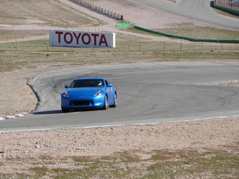 1992 Ford Taurus - A blue sports car navigates a curve on a race track, with a large TOYOTA sign visible in the distance.