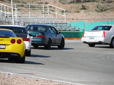 1992 Ford Taurus - A teal 1992 Ford Taurus sedan is seen from the rear on a race track, alongside other vehicles.