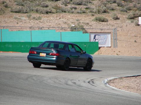 1992 Ford Taurus - A green 1992 Ford Taurus sedan navigates a turn on a race track, with a Bud Light sign visible in the background.