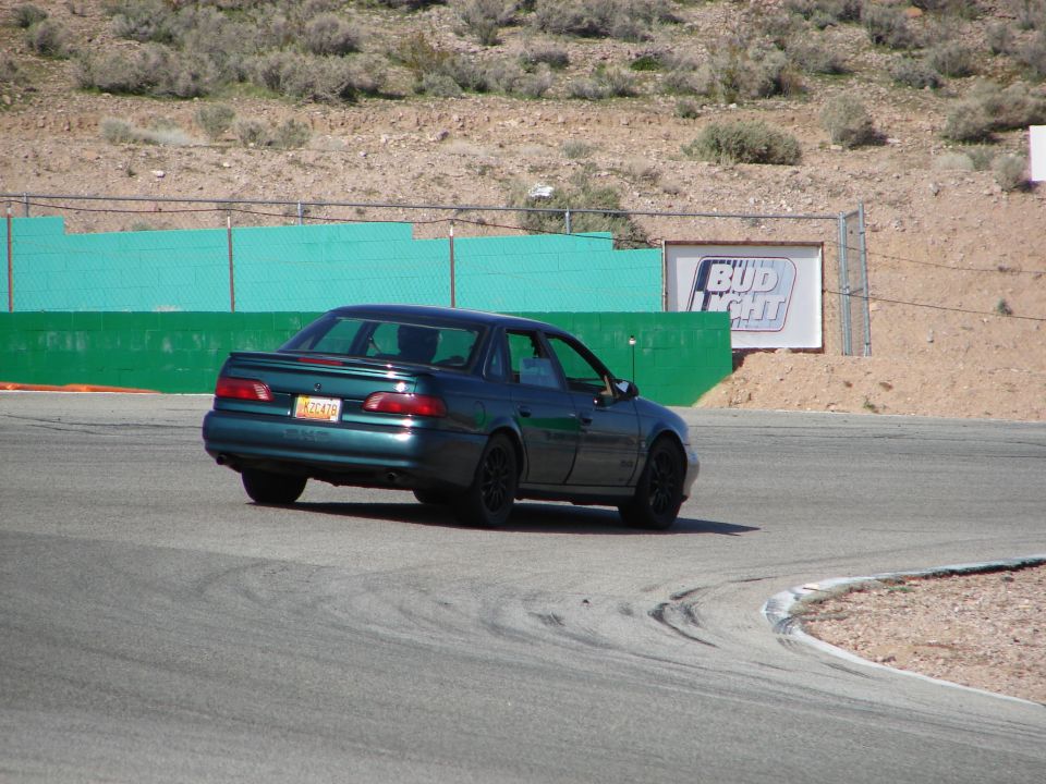 Green 1992 Ford Taurus sedan on a race track, viewed from the rear
