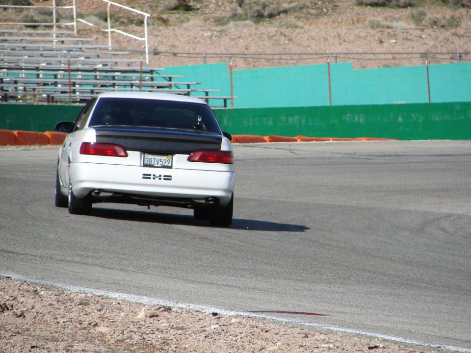 White sedan with a black spoiler and license plate 3BT V599 on a racetrack