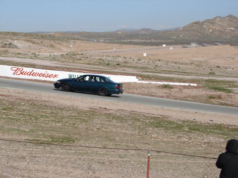 1992 Ford Taurus - A dark sedan is seen on a race track with a Budweiser advertisement in the background.
