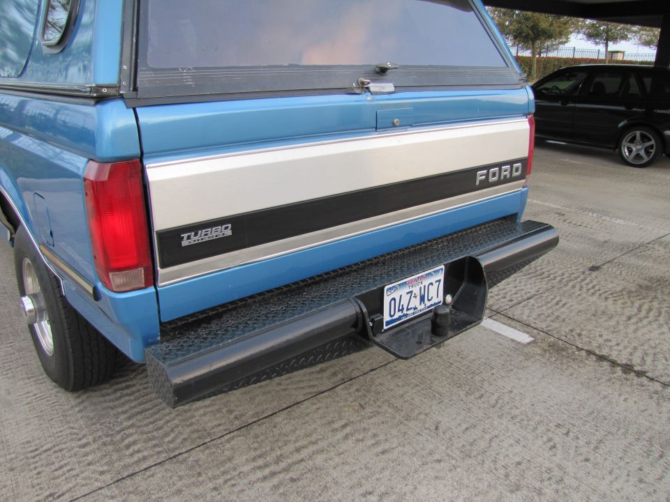 Blue Ford pickup truck with camper shell, rear view. Has 'Turbo' badge and 'Ford' lettering