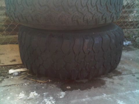 1985 Ford Bronco - Two tires are stacked on top of each other outdoors.