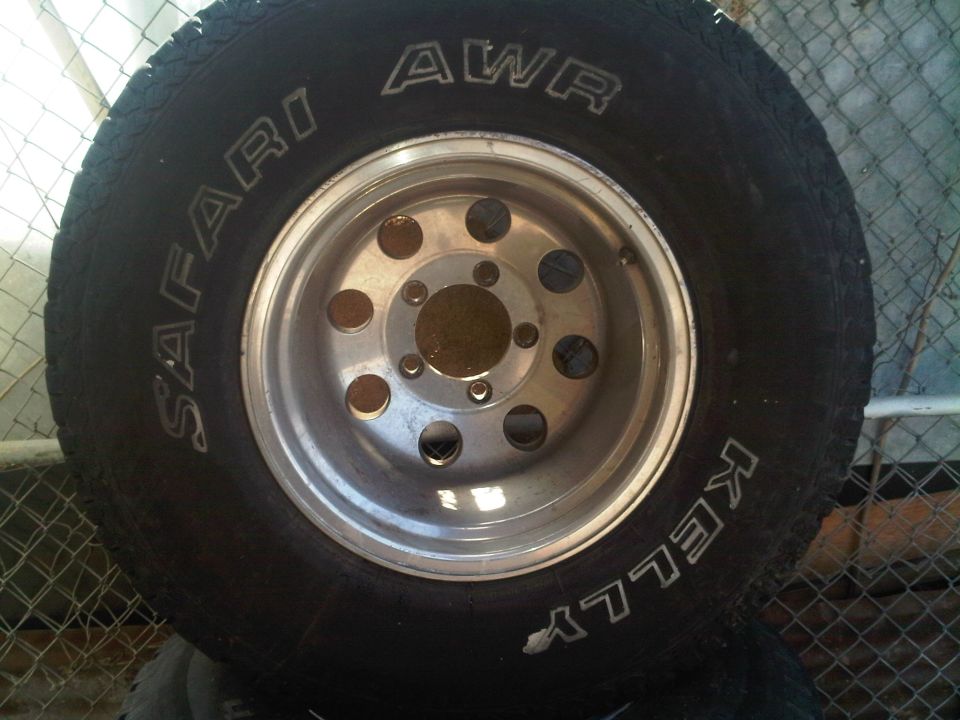 Tire with 'SAFARI AWR' and 'KELLY' text on a silver multi-hole wheel