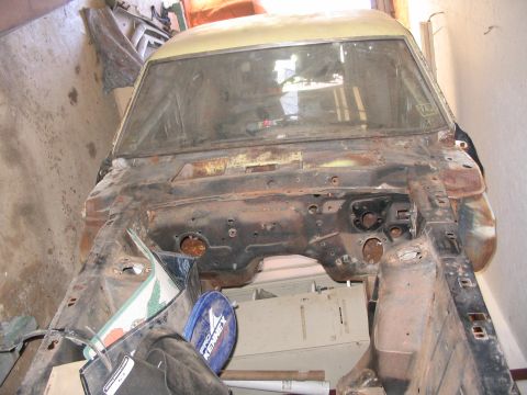 1970 Ford Mustang - This vehicle's front end is exposed, revealing a heavily rusted chassis and missing engine parts, stored indoors.