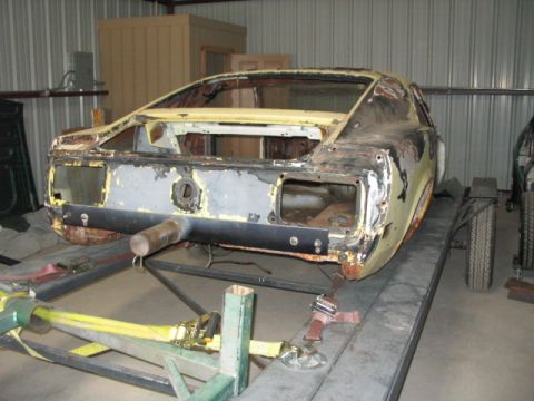 1970 Ford Mustang - The rear of a 1970 Ford Mustang body is visible, undergoing restoration on a lift.