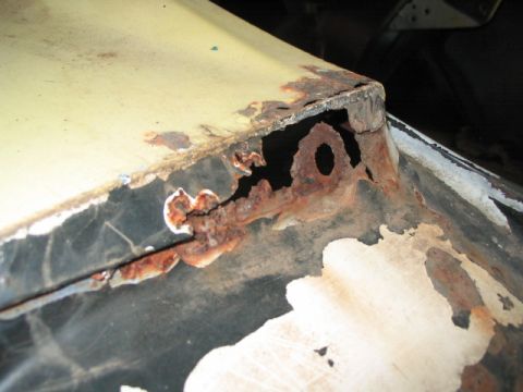 1970 Ford Mustang - This close-up shows significant rust damage on a vehicle's body panel, with metal corroded away.