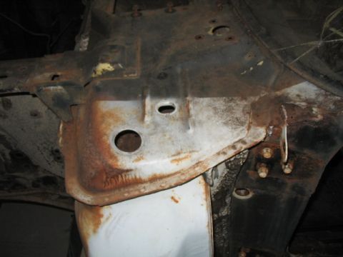 1970 Ford Mustang - Detail of a heavily rusted car frame, showing structural components and mounting points.