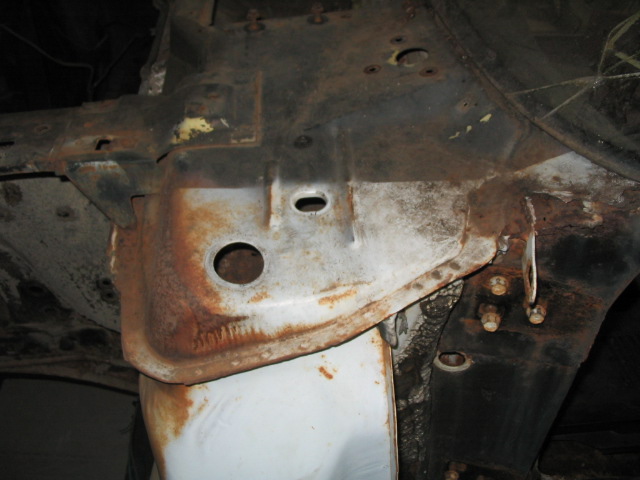 Close-up of rusted car frame with visible bolts and holes