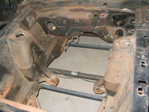 1970 Ford Mustang - The rusty chassis of a car, likely undergoing restoration, with the engine bay and front suspension area visible.