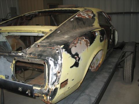 1970 Ford Mustang - Rear view of a 1970 Ford Mustang undergoing restoration, showing significant rust and body damage.