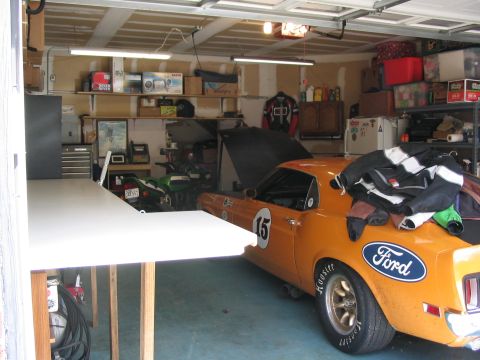 1970 Ford Mustang - A 1970 Ford Mustang race car is parked in a garage with a motorcycle and various items on shelves.