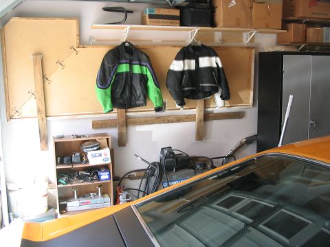 1970 Ford Mustang - Interior view of an orange car with motorcycle jackets and parts visible in the background of a garage.