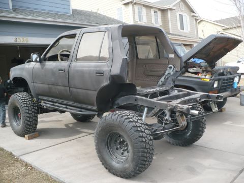 1979 Ford Bronco - A heavily modified SUV is shown with its body lifted off the frame, revealing its custom chassis and large off-road tires.