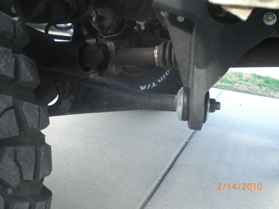 Close-up of a vehicle's suspension, showing the drive shaft and control arm