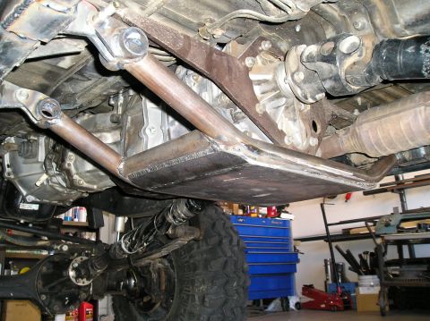 1986 Toyota Hilux - Underside view of a custom-fabricated transfer case skid plate and associated drivetrain components.