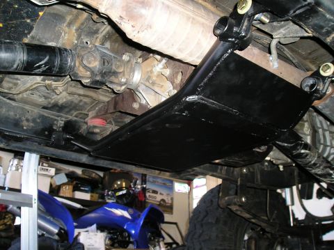 1986 Toyota Hilux - A black skid plate is mounted beneath the transfer case and driveshaft of an off-road vehicle.