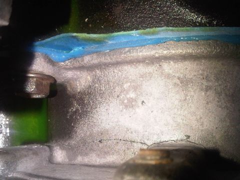 1996 Ford Bronco - Close-up of a cracked engine block showing blue sealant and a hint of green fluid, suggesting a potential leak or repair.