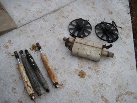 1992 Ford Mustang - Used car parts including shock absorbers, muffler, and fan blades laid out on a concrete surface.