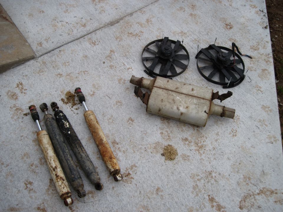 Four shock absorbers and a muffler with two fan blades on concrete