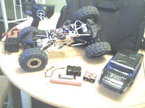 1989 Ford Bronco - Remote control car parts and accessories laid out on a table, including the chassis, transmitter, and batteries.
