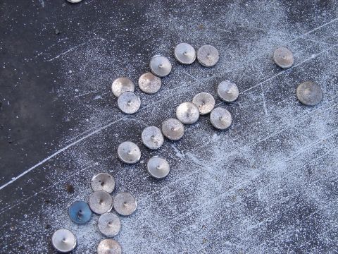 1973 Ford Ranchero - Numerous small, round metal fasteners are spread across a dusty, dark surface.