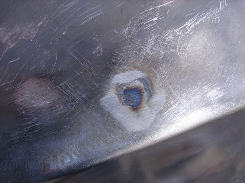 1973 Ford Ranchero - A close-up view of a metal panel showing a small, freshly welded patch with visible scratches.