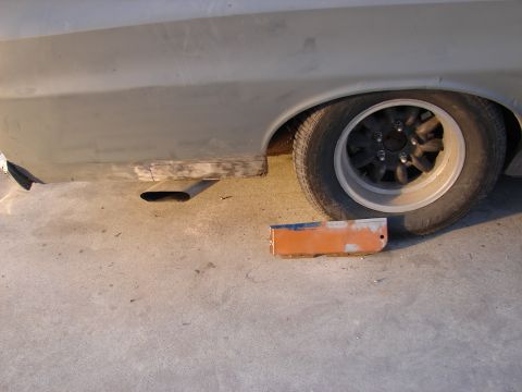 1973 Ford Ranchero - A car is undergoing repairs, with its exhaust pipe and rear wheel in view, and a detached part on the ground.