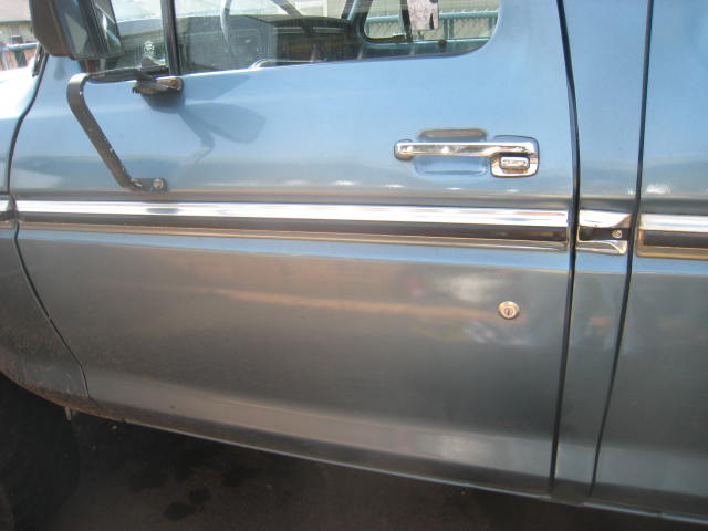 Close-up of light blue pickup truck front door with chrome trim and handle