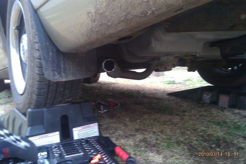 2000 Mercury Grand Marquis - The underside of a vehicle is visible, including the exhaust system and a tire supported by a jack stand.