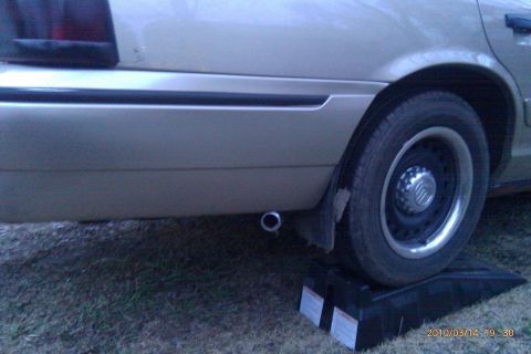 2000 Mercury Grand Marquis - Rear wheel and exhaust pipe of a 2000 Mercury Grand Marquis, seen from the side while on ramps.