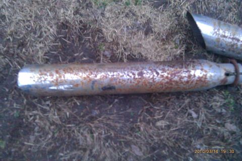 2000 Mercury Grand Marquis - A rusty exhaust pipe and its tip lie on the ground, showing signs of wear and tear.