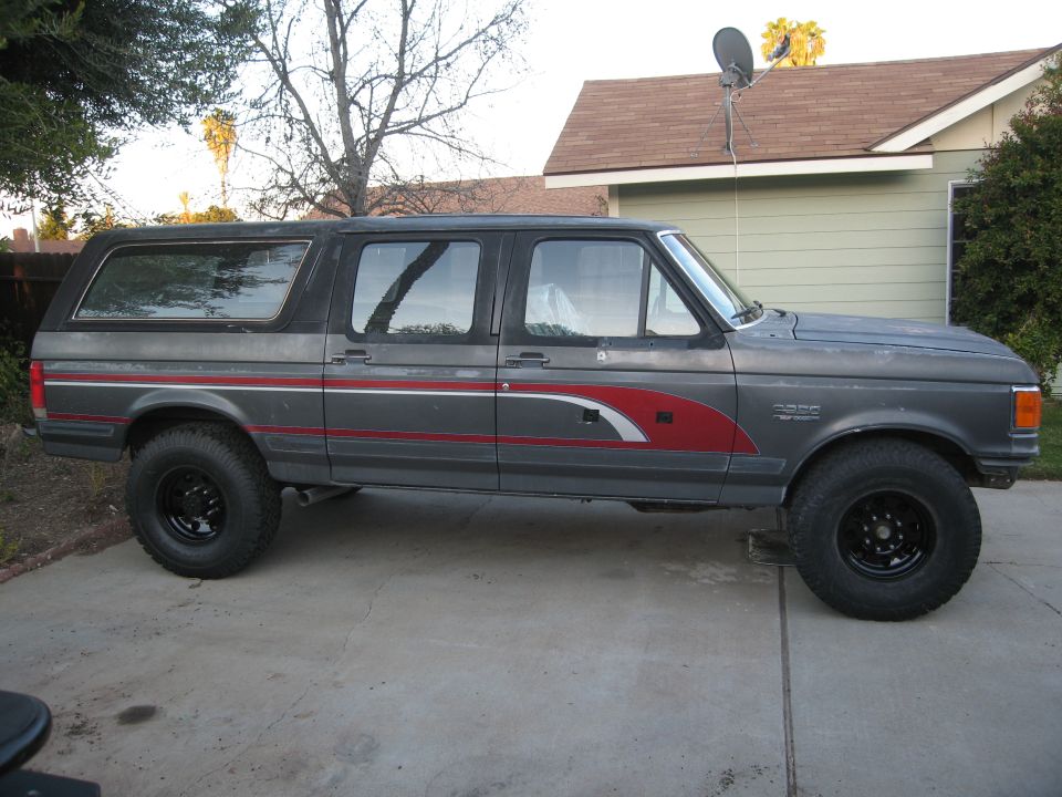 Side view of a gray 1986 Ford Bronco with red and white decals and black wheels